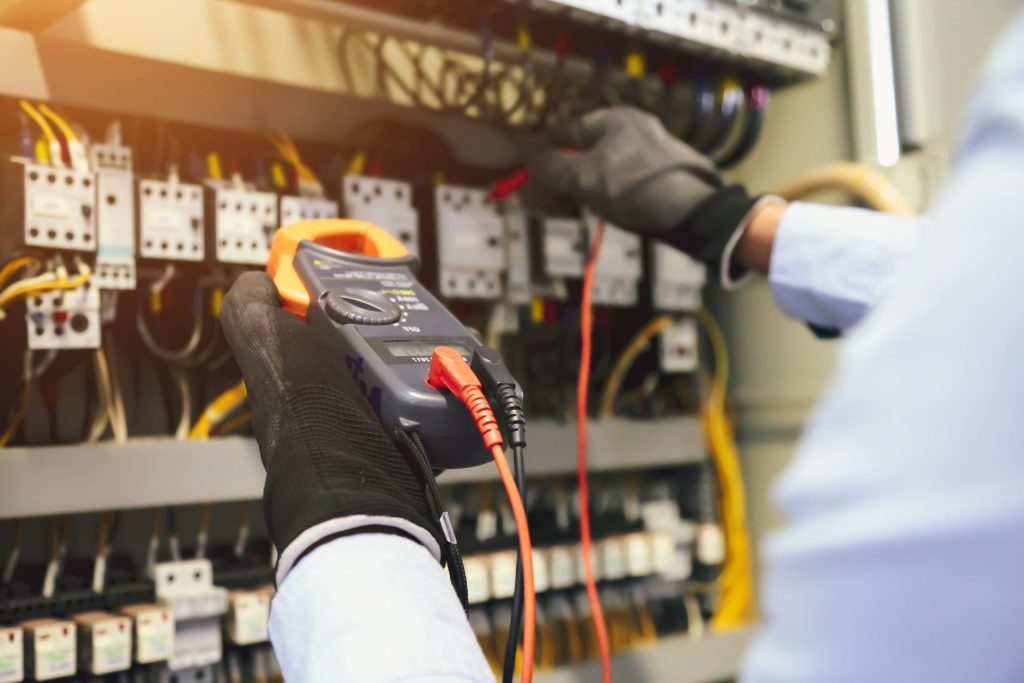 Personne tenant un multimètre sur un compteur d'électricité