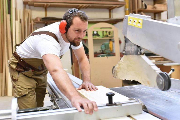 Un homme en formation de menuisier bois PVC aluminium dans un atelier avec une machine