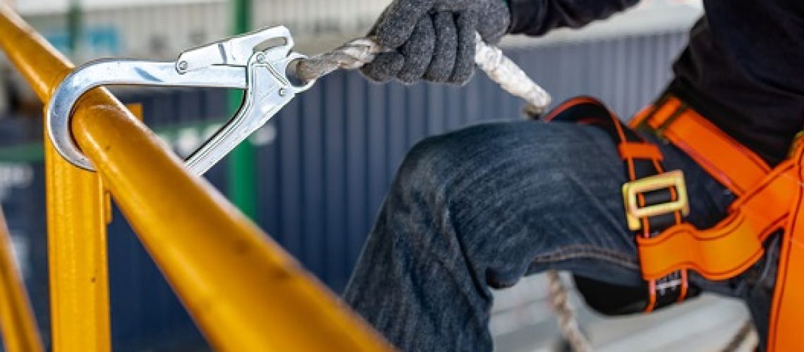 Construction worker wearing safety harness and safety line working on construction