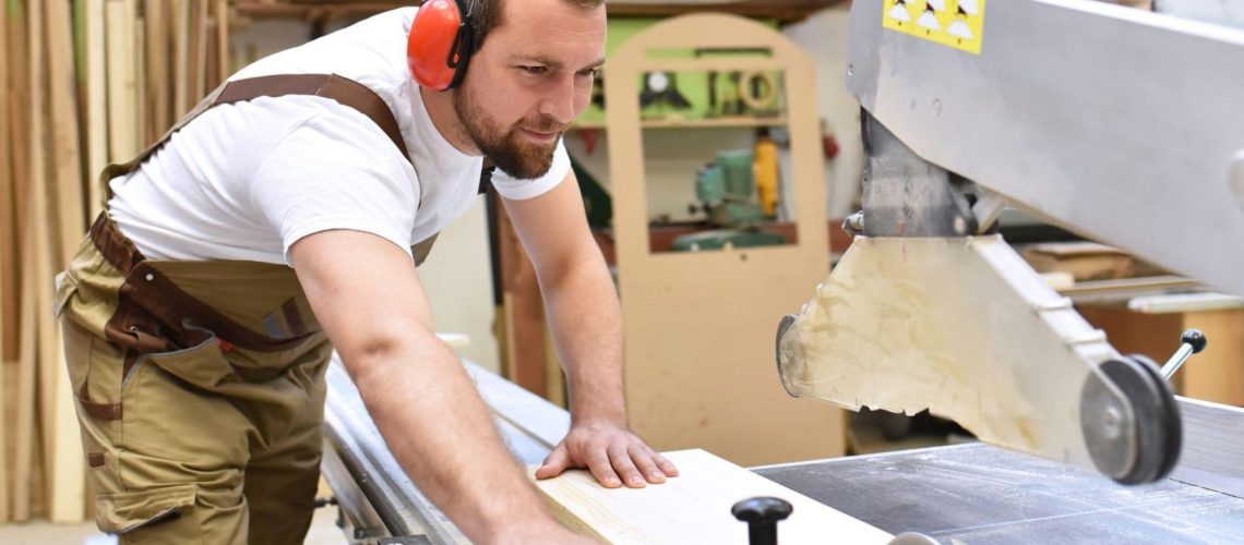 Un homme en formation de menuisier bois PVC aluminium dans un atelier avec une machine